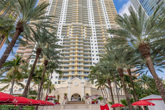 Front view of a high-rise building with multiple balconies and palm trees.
