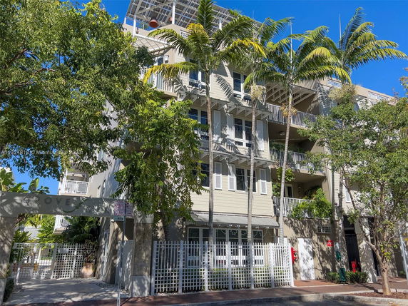 Front view of a multi-story residential building with balconies and gated entrance.