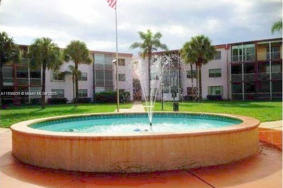 Front view of a multi-story apartment building with a fountain in front.