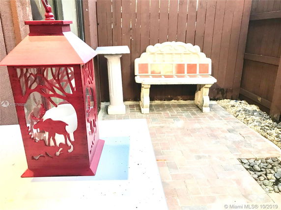 Outdoor area with a decorative red lantern and a stone bench on a paved surface.