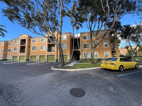 Front view of a three-story residential building with an attached garage and parking area.