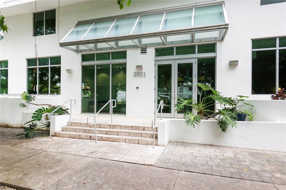 Front view of a modern building entrance with glass doors and steps.