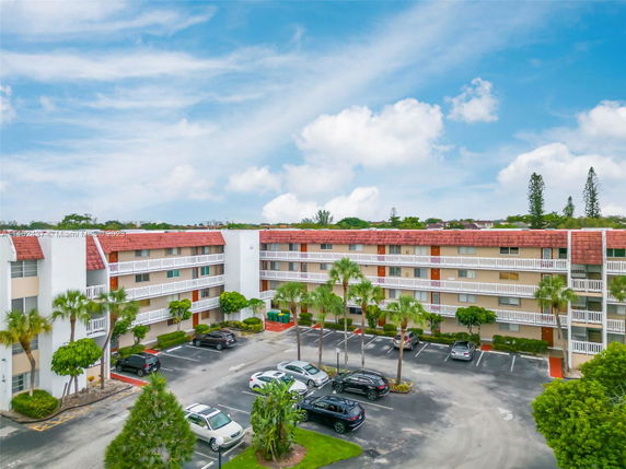 Front view of a multi-story residential building with balconies and parking area.