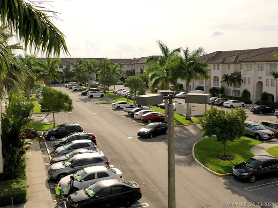Outdoor parking area with several cars and nearby residential buildings.