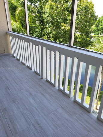 Balcony view with railing overlooking trees and a body of water.