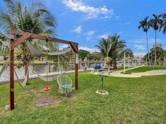 Outdoor play area with swings and hammock by a waterfront.