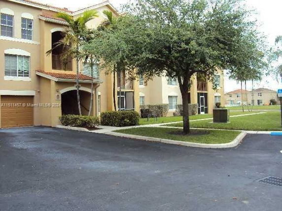 Front view of a multi-story residential building with arched windows and a garage.