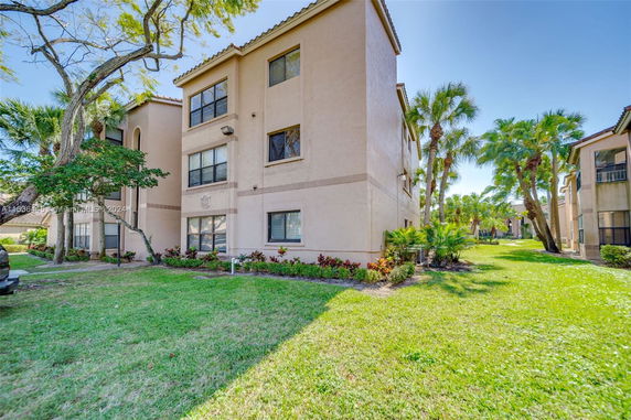 Front view of a multi-story residential building with a lawn in front.