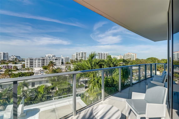 Panoramic view from a building balcony overlooking a cityscape with tall buildings and lush greenery.