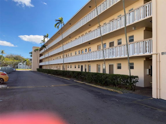 Front view of a multi-story apartment building with balconies in a sunny environment.