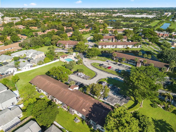 Aerial view of a residential area with multiple buildings, parking areas, and a swimming pool.