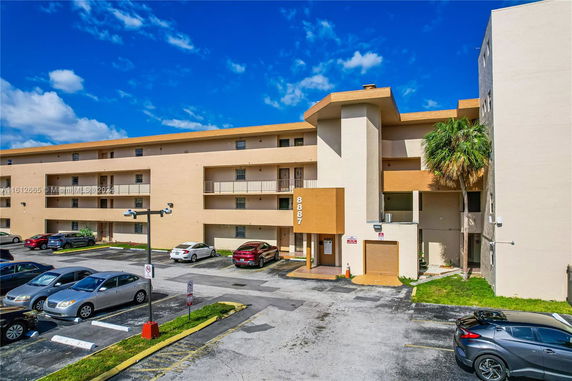 Front view of a multi-story apartment building with parking area.