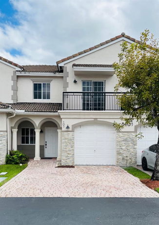 Front view of a two-story house with a single garage, balcony, and arched entrance.
