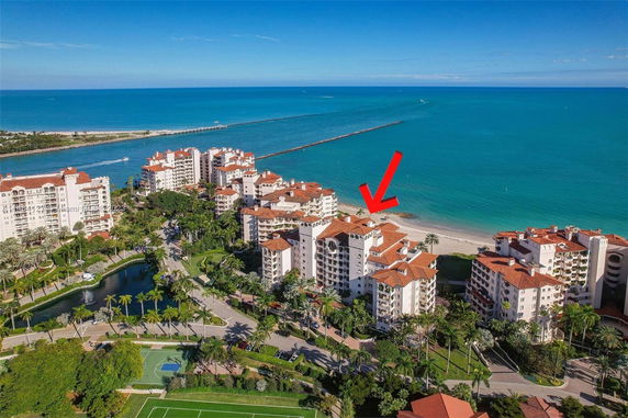 Aerial view of a seaside residential complex with multiple multi-story buildings and a beach in the background.