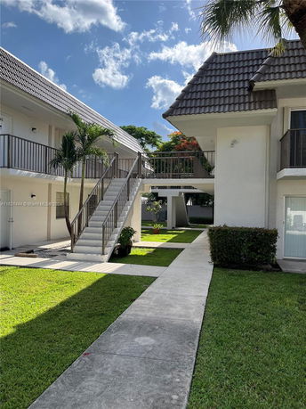 Front view of a two-story residential building with exterior staircases and a tiled roof.