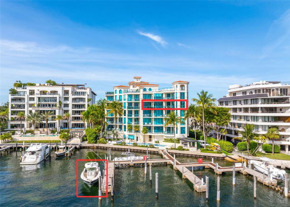Front view of waterfront apartment buildings with balconies and palm trees.