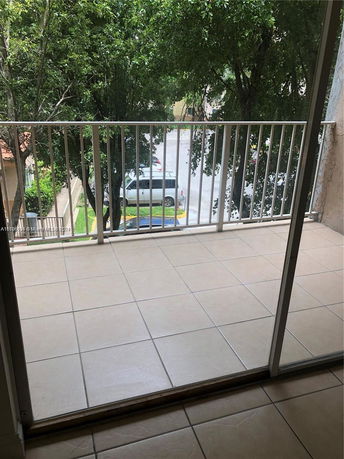 View of a balcony with a railing overlooking trees and parked cars.
