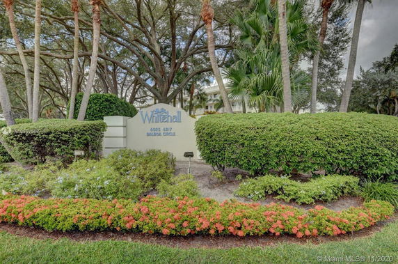 Front view of a building entrance sign with surrounding trees and bushes.