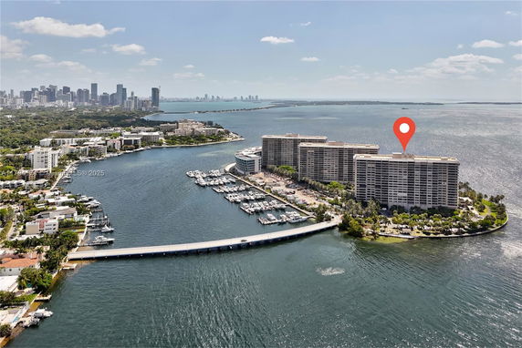 Panoramic view of waterfront buildings with marina and cityscape in the background.