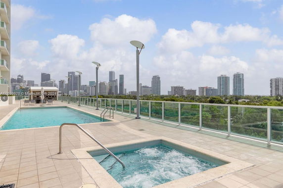 Outdoor rooftop swimming pool and hot tub area with city skyline view.