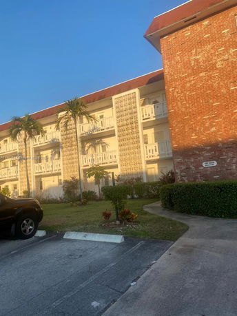 Outdoor parking area in front of a three-story apartment building.