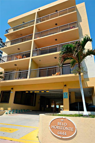 Front view of a multi-story building with balconies and covered parking area.
