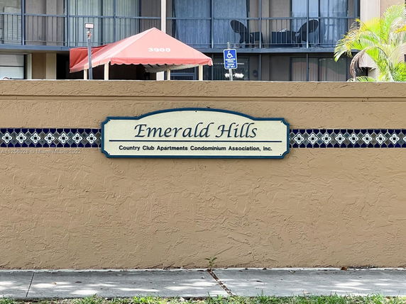 Front view of a multi-story apartment building with a sign reading 'Emerald Hills.'