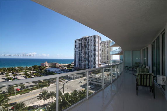 View from a balcony overlooking a cityscape with high-rise buildings and the ocean in the background.