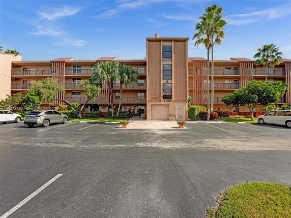 Front view of a multi-story residential building with parking area.