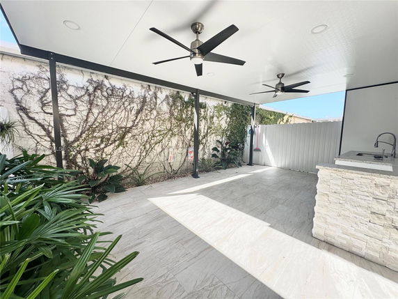 Covered patio area with ceiling fans and wall plants.