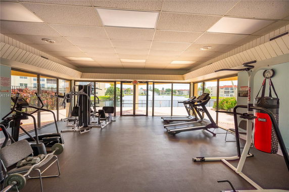 Indoor gym area with exercise equipment and large windows overlooking a view.