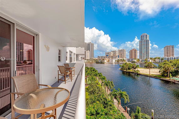 Balcony view overlooking water and city skyline with several high-rise buildings.