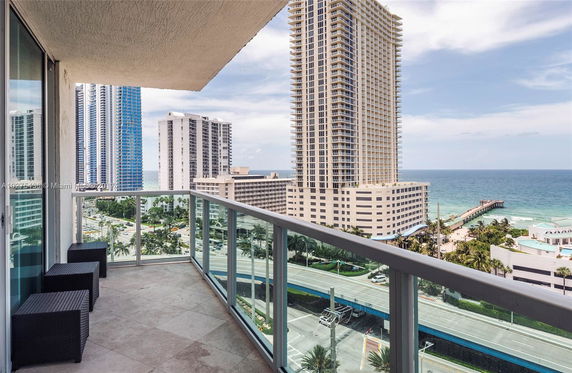 Balcony view with high-rise buildings and ocean in the background.