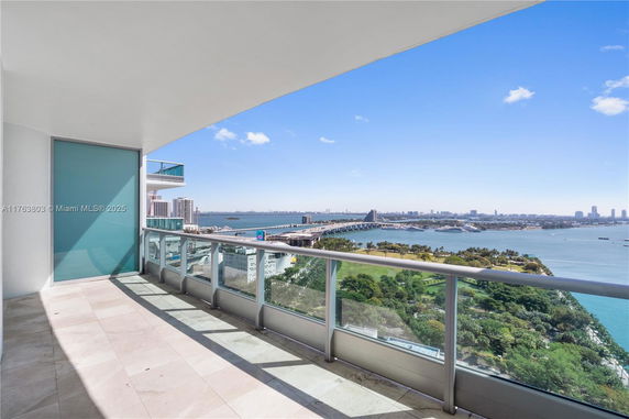 Panoramic view from a building balcony overlooking water and a cityscape.