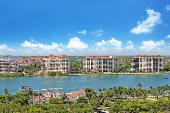View of multi-story waterfront buildings with greenery and waterway.