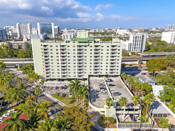 Front view of a multi-story residential building with balconies and parking area.