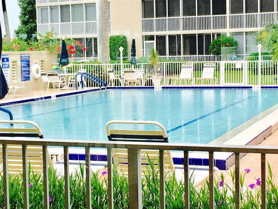 View of a swimming pool in front of a multi-story building with balconies.