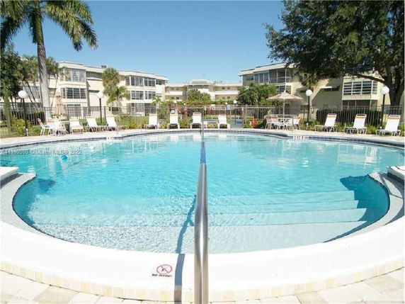 Outdoor swimming pool with surrounding lounge chairs and buildings in the background.