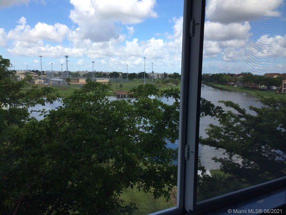 View through a window overlooking a lake and sports fields.