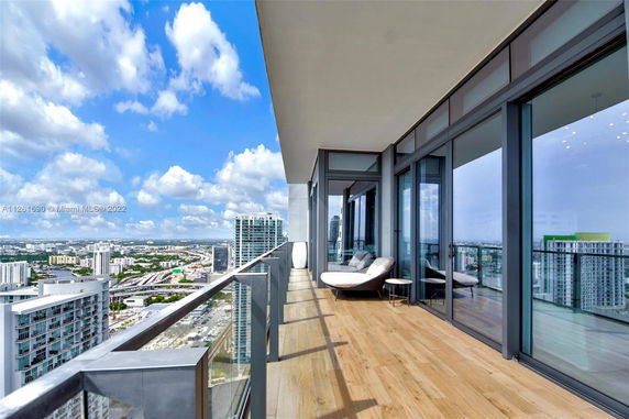 Balcony view from a high-rise building overlooking a cityscape with modern architecture.