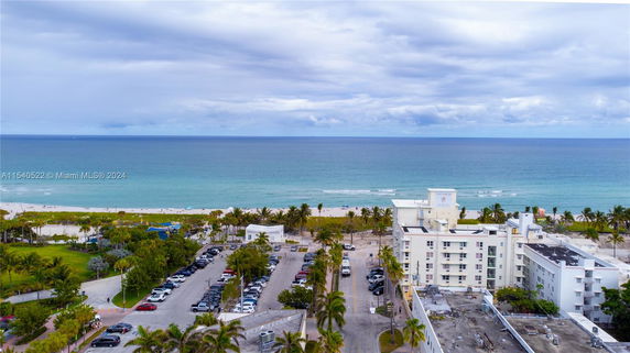 Aerial view of a coastal area with buildings, parking lots, and a beach leading to the ocean.