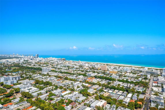 Panoramic view of a coastal city with buildings and beach along the shoreline.