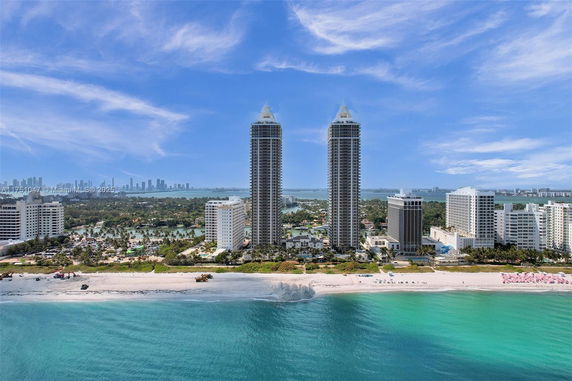 Aerial view of two high-rise buildings along the beachfront with cityscape in the background.