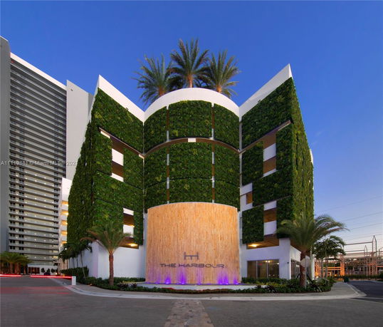 Front view of a modern building with a green facade and balcony features.