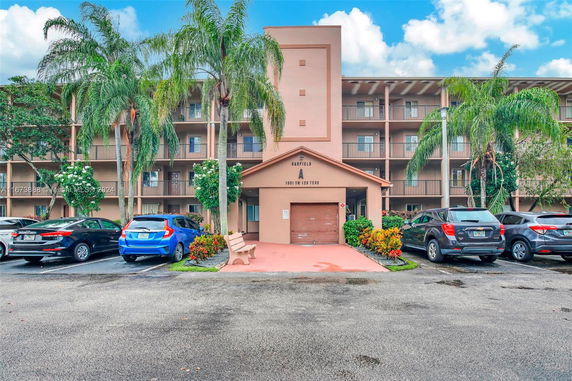 Front view of a multi-story residential building with palm trees in front.