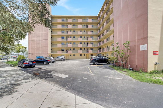 Front view of a multi-story residential building with parking area.