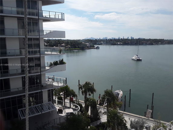 View from a building overlooking a waterfront area with a docked boat and a sailboat in the water.
