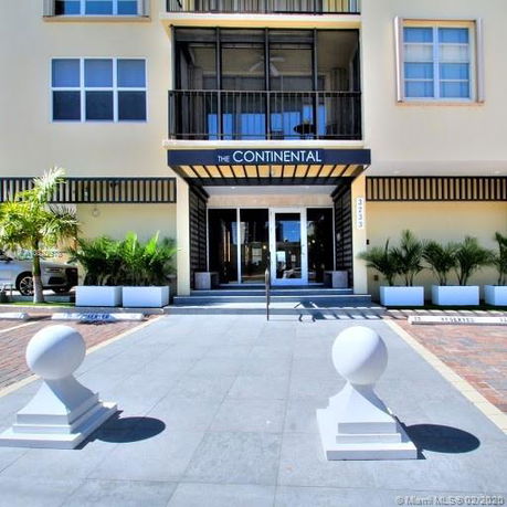 Front view of a building entrance with steps leading to glass doors.