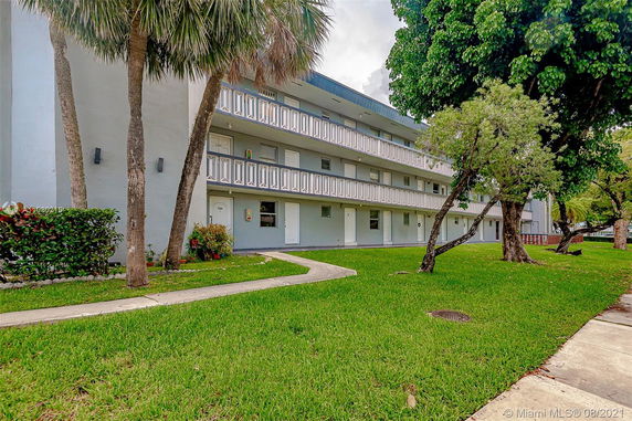 Front view of a multi-story building with balconies and surrounding greenery.