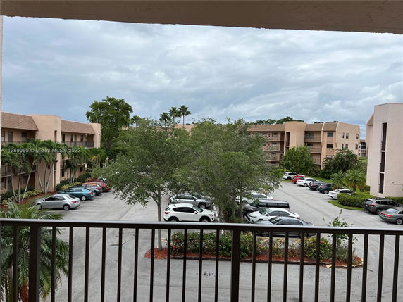 Outdoor parking area with multiple cars in front of residential buildings.
